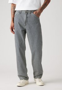 Pantalones a rayas con un diseño de pierna recta en azul y blanco, fabricados en tejido ligero. Presentan trabillas para cinturón y bolsillos laterales.