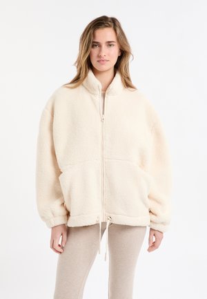 Cremefarbene Fleecejacke mit hohem Kragen, Reißverschluss und großen Fronttaschen. Verfügt über eine lockere Passform und einen Kordelzug am Saum.