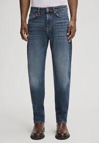 Granatowe dżinsy o prostym kroju, z czerwoną pętelką, klasycznym pięciokomorowym designem i delikatnym wybladzeniem na nogawkach.