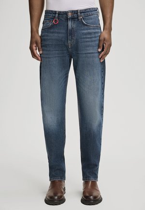 Donkerblauwe denim jeans met een rechte pasvorm, voorzien van een rode lus, klassiek vijf-pocket ontwerp en subtiele vervaging op de benen.