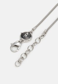 Silberner Metallkette-Lanyard mit einem runden schwarzen Knopf, der einen weißen Buchstaben "A" zeigt, und einem Krokodilverschluss zur Befestigung.