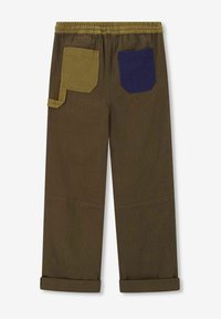 Bruine broek met een elastische tailleband, voorzien van twee achterzakken: één olijfgroen en één marineblauw. De manchetten zijn opgerold. Duurzame stof.