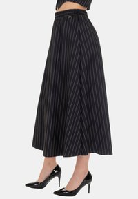 Gonna midi a righe nere con vita elastica, tessuto tinta unita e design fluido, abbinata a scarpe con tacco alto nere lucide.