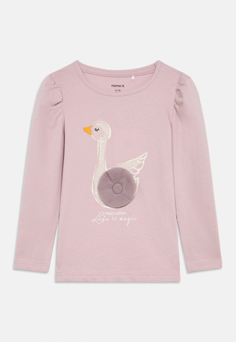 Rosa langermet skjorte med et hvitt og oransje brodert gås-design med et stoffsirkelakkent. Teksten sier "Livet er magisk."