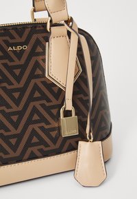 Braune Handtasche mit geometrischem Muster und einem beigen Lederboden, goldenen Beschlägen und einem dekorativen Schlossakzent. Verfügt über einen verstellbaren Schultergurt.