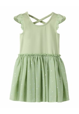 Robe sans manches vert clair avec épaules volantées, bretelles croisées dans le dos et jupe froncée ornée de petits points brillants.