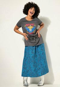 T-shirt gris avec un graphique coloré "Rock N Roll Rebel", associé à une longue jupe bleue à motifs et des bottines argentées. Ceinture noire à clous incluse.