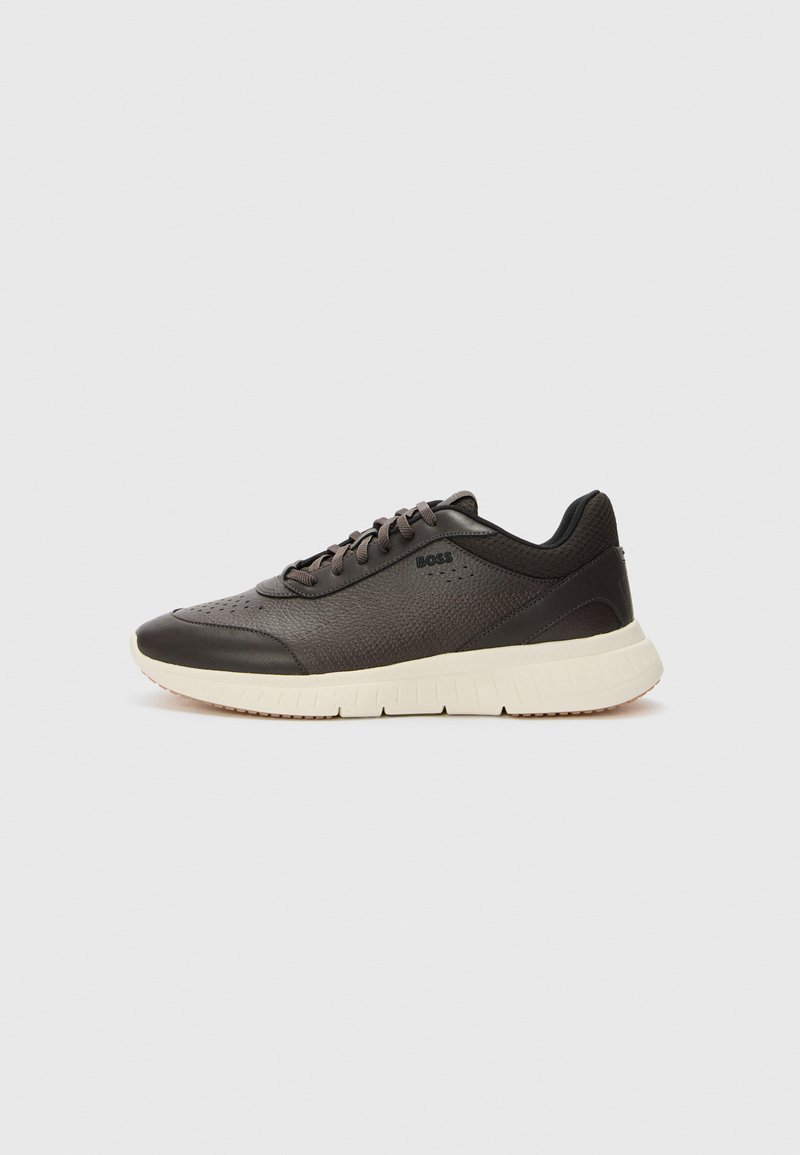 Mörkbruna sneakers med ett texturerat läderövre, perforerade detaljer och en lätt krämfärgad sula. Har snören och subtil branding.