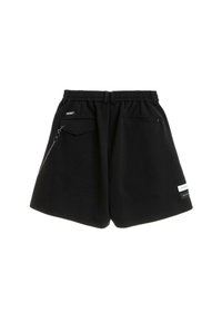 Pantalones cortos casuales negros con cintura elástica, bolsillo de solapa con cadena adjunta a la izquierda, bolsillo con cremallera a la derecha y pequeñas etiquetas blancas en la parte inferior derecha.