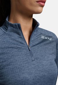 Pullover atletico leggero in tessuto blu heather, con colletto a zip fino a un quarto e un piccolo logo sulla spalla.