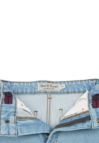 Ljusblå denimshorts med dragkedja, knappstängningar och en varumärkesetikett. Har kontrasterande röda och marinblå detaljer nära knapparna.