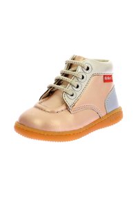 Botín de cuero marrón claro con detalles plateados, punta redonda, cordones de cinco ojetes y suela de goma naranja. Presenta el logotipo de Kickers en rojo.