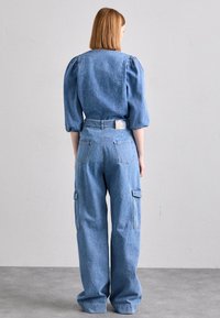 DenimjumpersFeatures a relaxed fit with puff sleeves, blue wash, large sidofickor, and a tailored back, showcasing a casual design.