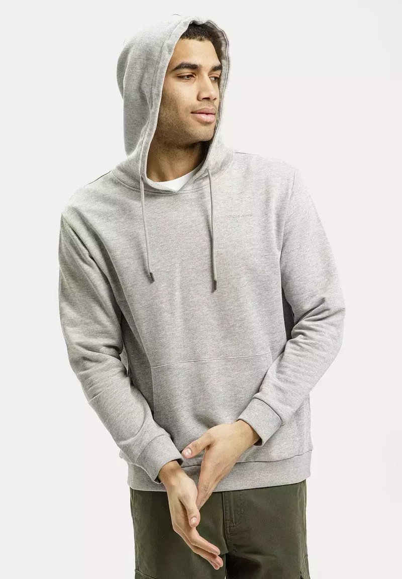 Szara bluza z kapturem, wykonana z miękkiego materiału, z przednią kieszenią, kapturem ze sznurkiem i ściągaczami przy rękawach. Stylizowana z wewnętrzną koszulą i luźnymi spodniami.