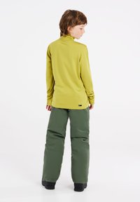 Lange mouw, limoen groene top gecombineerd met wijde, olijfgroene broek. De outfit is gemaakt van glad, rekbaar materiaal met minimale naden.