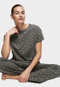 Grau Baumwoll-Pyjama-Set mit kurzen Ärmeln und lockeren Hosen, das ein verstreutes Muster aus kleinen pinken Herzen aufweist.