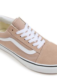 Beżowe płócienne trampki z białymi sznurówkami, z białym paskiem po boku i czarną podeszwą. Zauważalne detale przeszyć wzdłuż szwów.