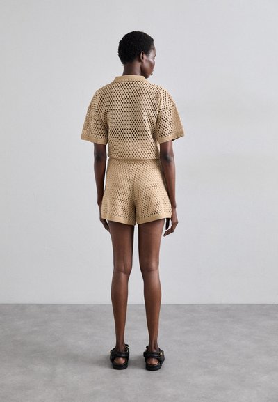 Beige crochet knit outfit featuring a short-sleeve top and matching shorts. The material has a mesh-like pattern with a relaxed fit.