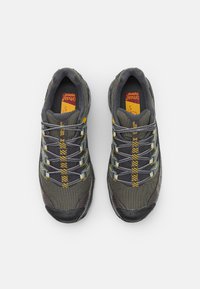 Grijze wandelschoenen met een bovenwerk van mesh en rubber, gele en grijze accenten en een gestructureerde zool met veters die door verstevigde oogjes lopen.