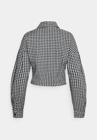 Chemise gingham noir et blanc raccourcie avec un col pointu, des manches longues et des poignets froncés, présentant un motif en damier sur l'ensemble.