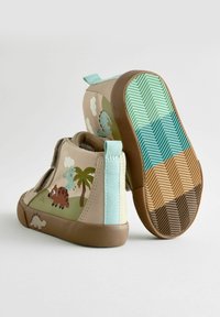 Stivali in tessuto beige con motivi di dinosauri e palme, con un accento turchese chiaro sul tallone e una suola a zigzag multicolore.