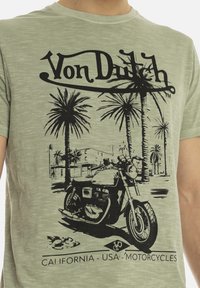 T-shirt en coton vert clair avec un graphisme noir représentant une moto et des palmiers, avec le texte "Von Dutch" et "CALIFORNIA - USA - MOTORCYCLES".