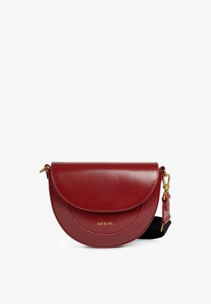 Červená kožená kabelka crossbody s oblým chlopňovým uzáverom, zlatou kovovou výbavou a odnímateľným čiernym popruhom. Na prednej strane je vyrazené meno značky.