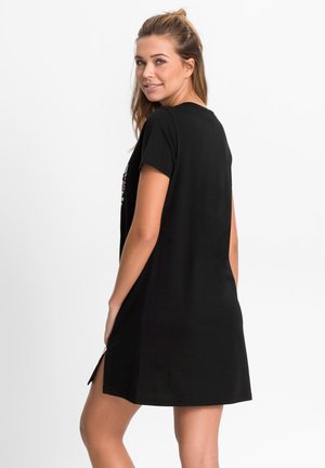 Abito nero a maniche corte con una forma leggermente svasata e fessure laterali, caratterizzato da dettagli a stampa floreale sul davanti. Tessuto dalla texture liscia.
