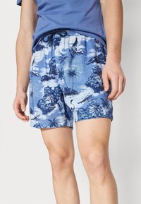 Bañador azul hecho de una tela ligera, con un patrón tropical que incluye palmeras y barcos. Cintura elástica con cordón.