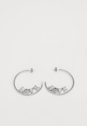 Strieborné kruhové náušnice s trojrozmerným nápisom "LÁSKA" so zdobením a lesklým povrchom.