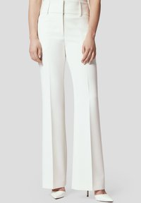 Białe, wysokogatunkowe, szerokie spodnie o wysokim stanie, wykonane z gładkiego materiału, z wyraźnymi liniami i subtelnymi bocznymi kieszeniami. Zestawione z szpilkami o spiczastym nosku.