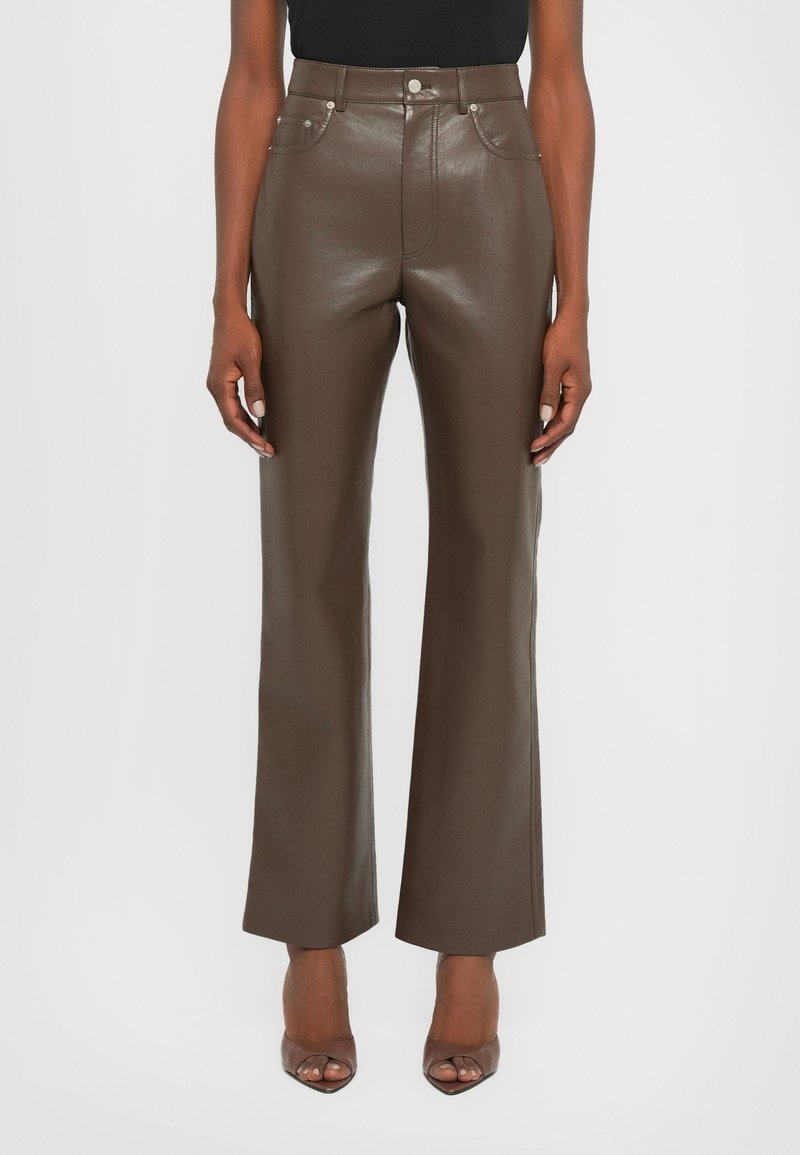 Brown leather high-waisted pants with a straight-leg design, featuring front pockets and shiny texture. Paired with open-toe heels.
