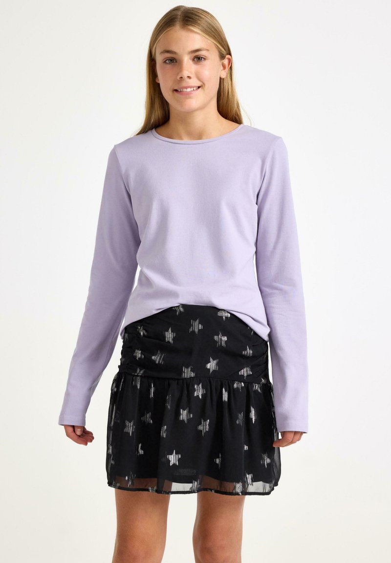 Lavendel langærmet skjorte parret med en sort nederdel med sølvstjerne mønstre, rynket talje og lagdelt flæsehel.