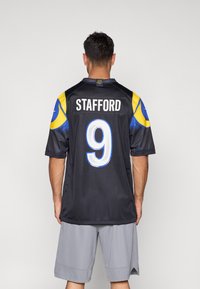 Μαύρη φανέλα ποδοσφαίρου με μπλε και κίτρινες λεπτομέρειες, αριθμός 9 σε λευκό στο πίσω μέρος, όνομα "STAFFORD" από πάνω, κοντά μανίκια και άνετη εφαρμογή.