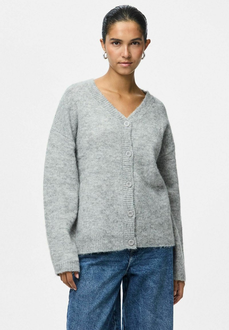 Sivi vuneni kardigan s V-izrezom, dugim rukavima i s šest velikih gumba sprijeda. Mekana tekstura, rebraste manžete i detalj na rubu.