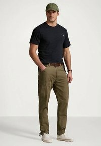 Mörkgrå kortärmad skjorta, olivgröna cargobyxor med fickor, brun bälte och ljusa sneakers, toppat med en matchande grön keps.