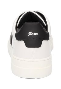 Weiße Leder-Sneaker mit schwarzen Akzenten an der Ferse, weichem Innenfutter, dicker weißer Sohle und silbernem Logo-Detail auf der Rückseite.