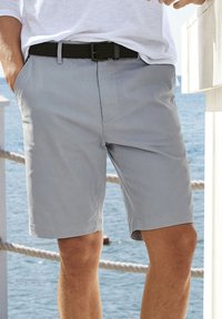 Pantaloni corti grigi chiari realizzati in tessuto di misto cotone, con una texture liscia, tasche laterali e una cintura intrecciata nera. Design semplice con bordi rifiniti.