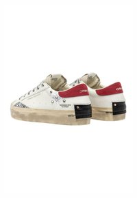 Sneakers bianche in pelle con accenti grigi, una linguetta rossa sul tallone e una texture vissuta. Presentano dettagli neri sul tallone e stampe del logo.
