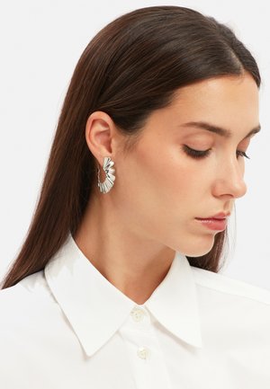 Sølv hooped øreringe med et tekstureret, bladlignende design. Øreringene er mellemstore og har en poleret finish.