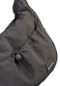 Grau gewebter Beutel mit gerafftem oberen Teil, ausgestattet mit einem Zugverschluss und einem kleinen schwarzen Etikett. Weiche Textur mit zerknittertem Aussehen.