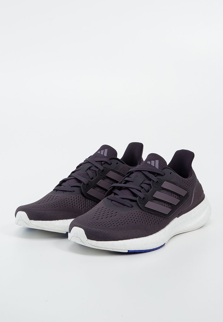 Une paire de chaussures de course violettes foncées avec des rayures noires, des semelles rembourrées blanches et des lacets, sur un fond blanc.