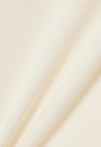 Tissu de couleur crème avec une texture lisse et un motif de tissage diagonal subtil, présenté en plis doux.