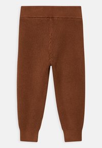 Pantalones de punto marrones con una cintura acanalada y una superficie texturizada, que presentan piernas ajustadas y un ajuste ceñido en el tobillo.