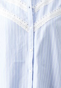 Light blue button-up shirt with white vertical stripes, featuring lace accents along the shoulders and a smooth cotton texture.