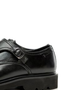 Schwarzer Lederschuh mit einem eleganten Design, einer Schnallenakzentuierung, strukturierten Oberflächen und einer stabilen, geriffelten Gummisohle.