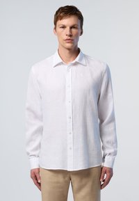 Camicia bianca in lino a maniche lunghe con colletto button-down e bottoni frontali, con un logo sottile nella parte superiore sinistra.