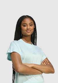 Camiseta atlética de manga corta azul claro con un sutil logo triangular en el pecho. Tejido suave y corte relajado, adecuada para ropa deportiva.