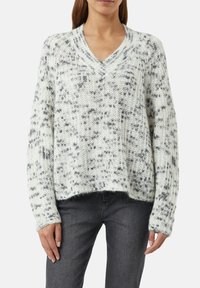 V-neck, oversized sweater in white with gray speckled pattern. Chunky knit texture with ribbed cuffs and hemline, offering a relaxed fit.