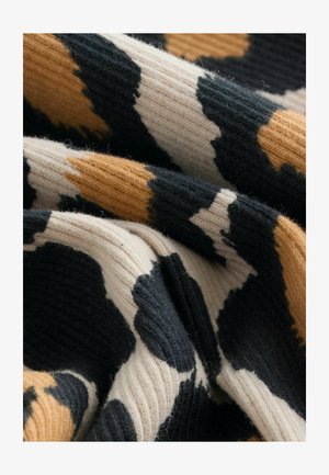 Rippstoff mit einem Kuhmuster in Schwarz, Creme und Senfgelb. Weiche Textur mit einem geschichteten, gefalteten Aussehen.